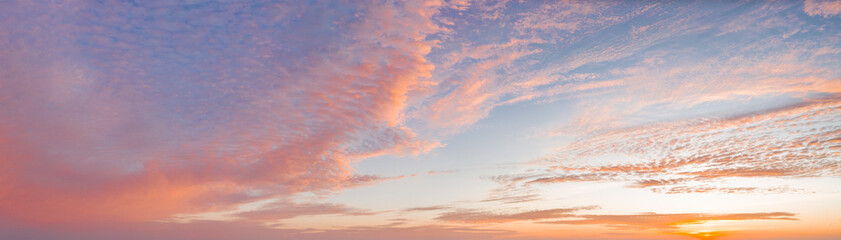 intense dramatic panoramic sunset with cirrus clouds illuminated by red sunbeams