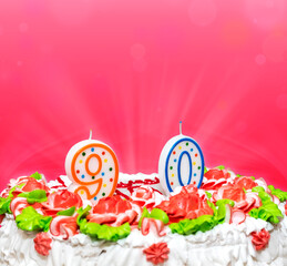 Birthday cake, decorated with colored and candles, numbers 9 and 0. Jobs ninety years on a pink...