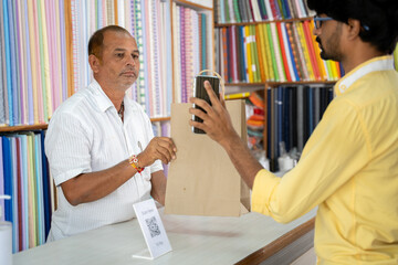 Customer using digital payment method scan to pay at cloth store to send money and shoing to...