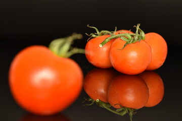 Several ripe organic, juicy, tasty smoothie tomato, macro, bright red, on a black background.