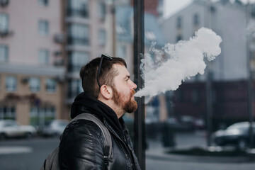 man with a backpack smokes in the city