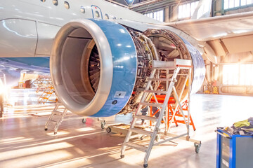 Opened aircraft engine in the hangar, illuminated by bright sunlight from outside the gate. - obrazy, fototapety, plakaty