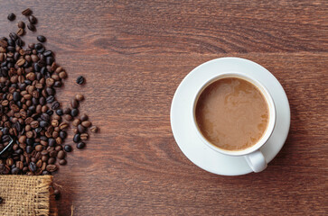 cup of coffee and coffee beans in a sack on  Brown background, top view