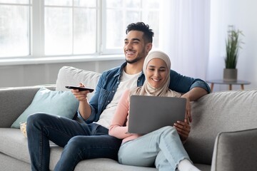 Happy arab man with remote hugging muslim woman with laptop