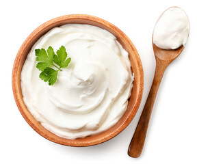 Sour cream in a wooden plate and spoon on a white background, isolated. The view from top