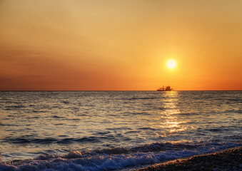Obraz premium Golden sunset over the Black Sea (Adler, Russia) in summer. An enchanting picture with the sea sparkling from the sun on a summer evening. The disc of the sun is low above the surface of the water 