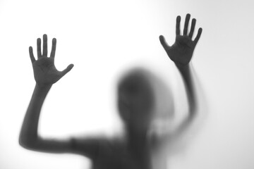 Silhouette scared boy stand behind glass door. Teen problems, negative emotions concept.