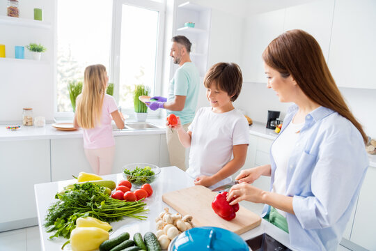 Photo of happy smiling positive lovely family cooking together little son helps mom with vegetables at home house