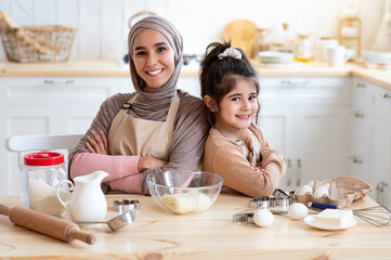 Happy Islamic Mom And Little Daughter Posing In Kitchen While Baking Together