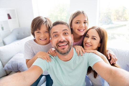 Photo portrait of friendly family taking selfie sitting together on sofa dad keeping camera smiling overjoyed with wife son and daughter