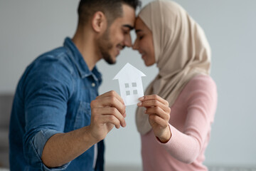 Young muslim couple holding paper house, selective focus