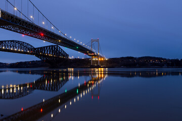 Fototapeta na wymiar Low angle view of the 1970 suspension Pierre-Laporte Bridge and 1919 steel truss Quebec Bridge over the St. Lawrence River seen during a blue hour early morning, Quebec City, Quebec, Canada