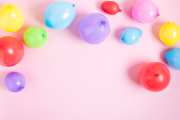 Birthday background with multicolored balloons on pastel pink background.