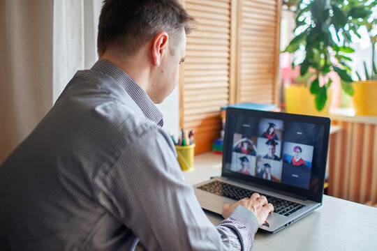 Virtual graduation and convocation ceremony. Laptop screen with happy students wearing graduation gown and cap receiving congratulation from professor during online video call, distant education