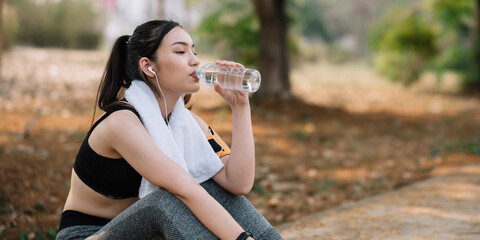 Young woman athlete takes a break, drinking water, out on a run on a hot day.