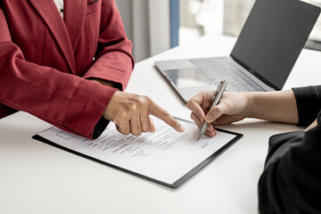 The HR department is pointing to the documents for the job applicant to sign on the contract after attending a job interview with the department manager and being selected for the job.