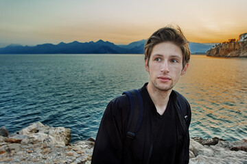 Antalya at beginning of tourist season in early spring, young white man strolls near sea at sunset.