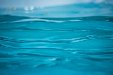 Naklejka na ściany i meble Blue water in the pool. Patterns and reflections and on the water surface. Splashing drops.