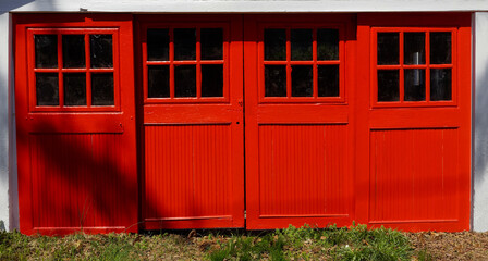 Newly red painted, old-fashioned sliding garage door with windows.