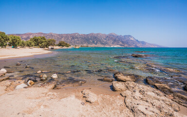 Fototapeta na wymiar Rocks on beach of Kardamena resort. Kos island, Greece. Sunny day, no people.