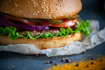 Hamburger lies on the board on a dark background