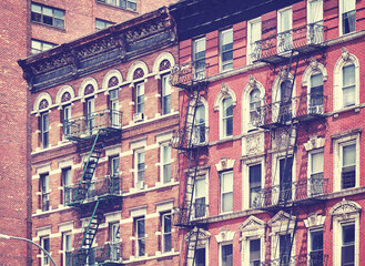 Fototapeta premium Old brick buildings with fire escapes, color toning applied, New York City, USA.