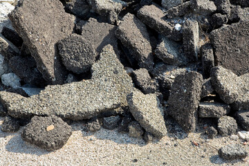 Cracked asphalt pieces after demolition of a road surface in a construction site for renovation ready to be recycled