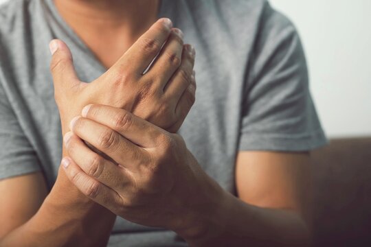 Image of a man in a gray shirt pain in hands,arthritis inflammation,wrist symptomatic.Office Syndrome.