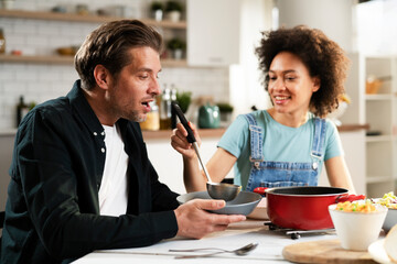 Boyfriend and girlfriend eating lunch together at home. Husband and wife enjoying in delicious food..