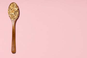 wooden spoon and oatmeal on pink background