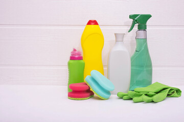 colored bottles of household cleaning liquid, colored rags and green gloves