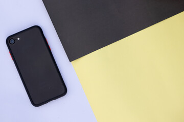 A Mobile phone on multi-colored paper background.