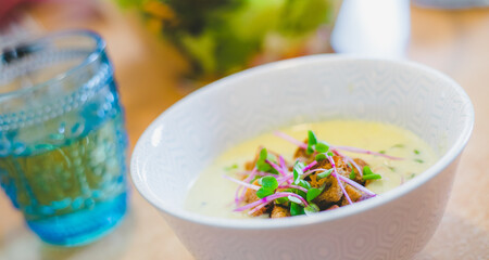 Healthy and fresh homemade broccoli soup with croutons and radish sprouts, served in white ceramic bowl