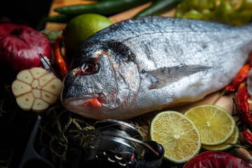 Fresh sea fish with olive oil, spices and lemon ready for cooking. Dorado or sea bream fish.