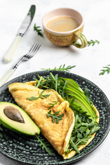 Omelette with avocado and arugula on plate. Healthy diet food for breakfast. Frittata - italian omelet, vertical image Top view