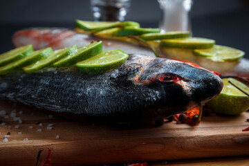 Fresh uncooked dorado or sea bream fish with lemon slices, spices, herbs and vegetables. Mediterranean cuisine. 