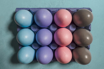 Painted multicolored Easter eggs in pastel gradient shades placed in a purple box on a blue background. Stylish Easter concept