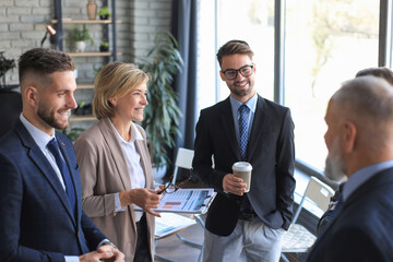 Group of business collegues discussing ideas and planning work during coffee break in office.