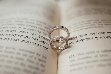 Two silver engagement wedding rings lie on an open bible book