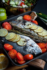 Dorado fish is cooked in a black grill pan. Seafood and vegetables. Seasonings and spices.