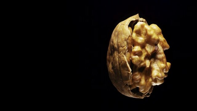 broken in half walnut on a black background rotates. Close-up.