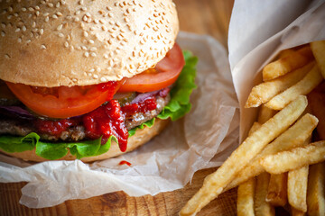Hamburger with a knife lies on a board on a dark background