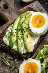 Sandwich with fresh green avocado, egg and soft cheese on Cereal Bread. vertical image Top view.
