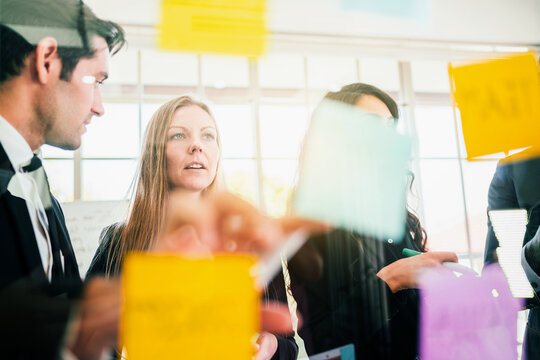 Group of successful business teamwork. Brainstorm meeting with colorful sticky paper note on glass wall for new ideas. Using agile methodology and do business. Brainstorming in a tech start-up office.