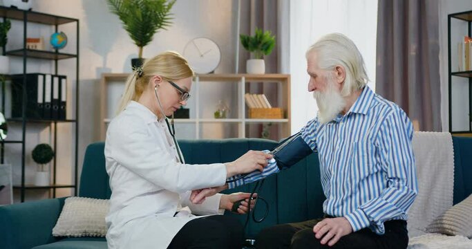 Pretty smiling friendly qualified female doctor measuring old man's pressure using tonometer and is satisfied from results,medicine concept