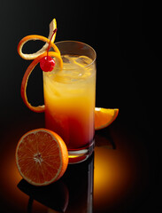 Cocktail tequila sunrise on a black reflective background.