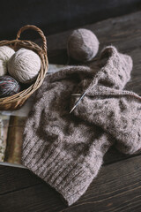 Obraz na płótnie Canvas Hand knitting with needles and yarn balls in a basket on a dark background. Concept for handmade and hygge slow life.