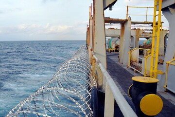 Barbed wire or razor wire attached to the ship hull, superstructure and railings to protect the...