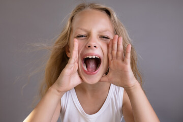 Portrait of a pretty little blonde girl showing emotions and screaming