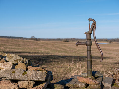 Old water pump with handle by a well in rural farmland. Shot in Sweden, Scandinavia
